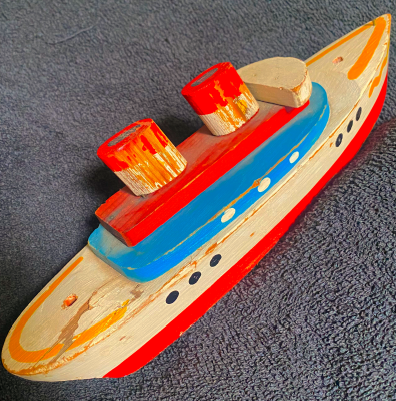 A wooden toy boat on the floor