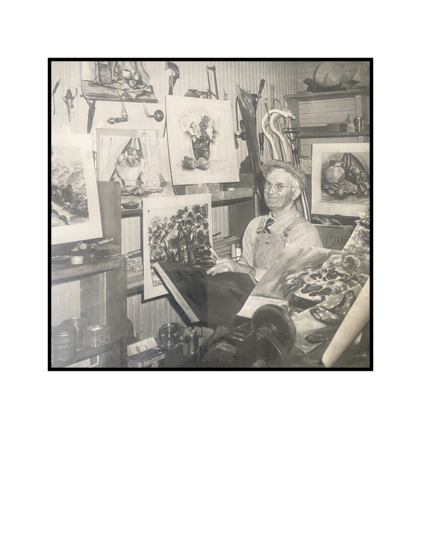 A man sitting in front of some paintings.