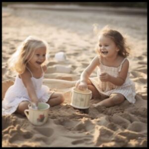 Two little girls sitting on the beach and playing with sand